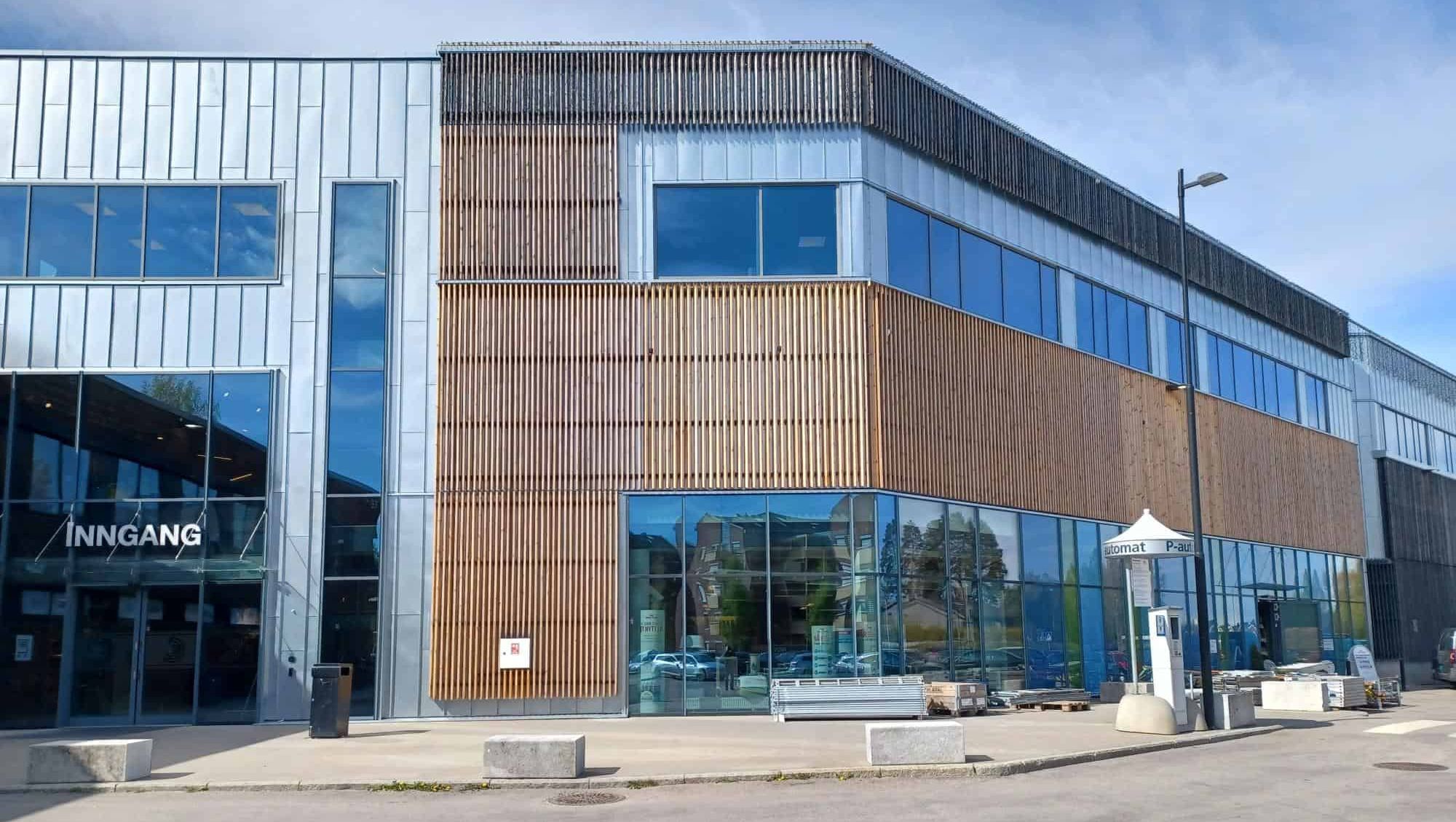 Større bygg med kombinasjon av glass, metall og trespiler i moderne arkitektur.