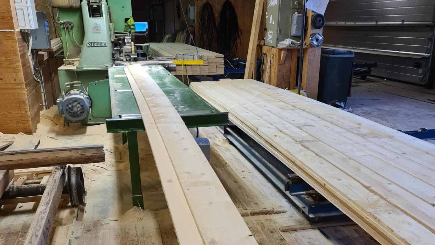 Treplanker mates gjennom maskin for nøyaktig kutting og forming i snekkerverksted.
